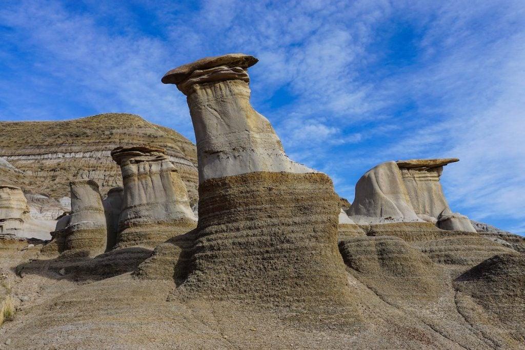 A small group of dark sandstone hoodoos with mushroom-shaped caprocks rising from the Alberta badlands between Drumheller and East Coulee.
