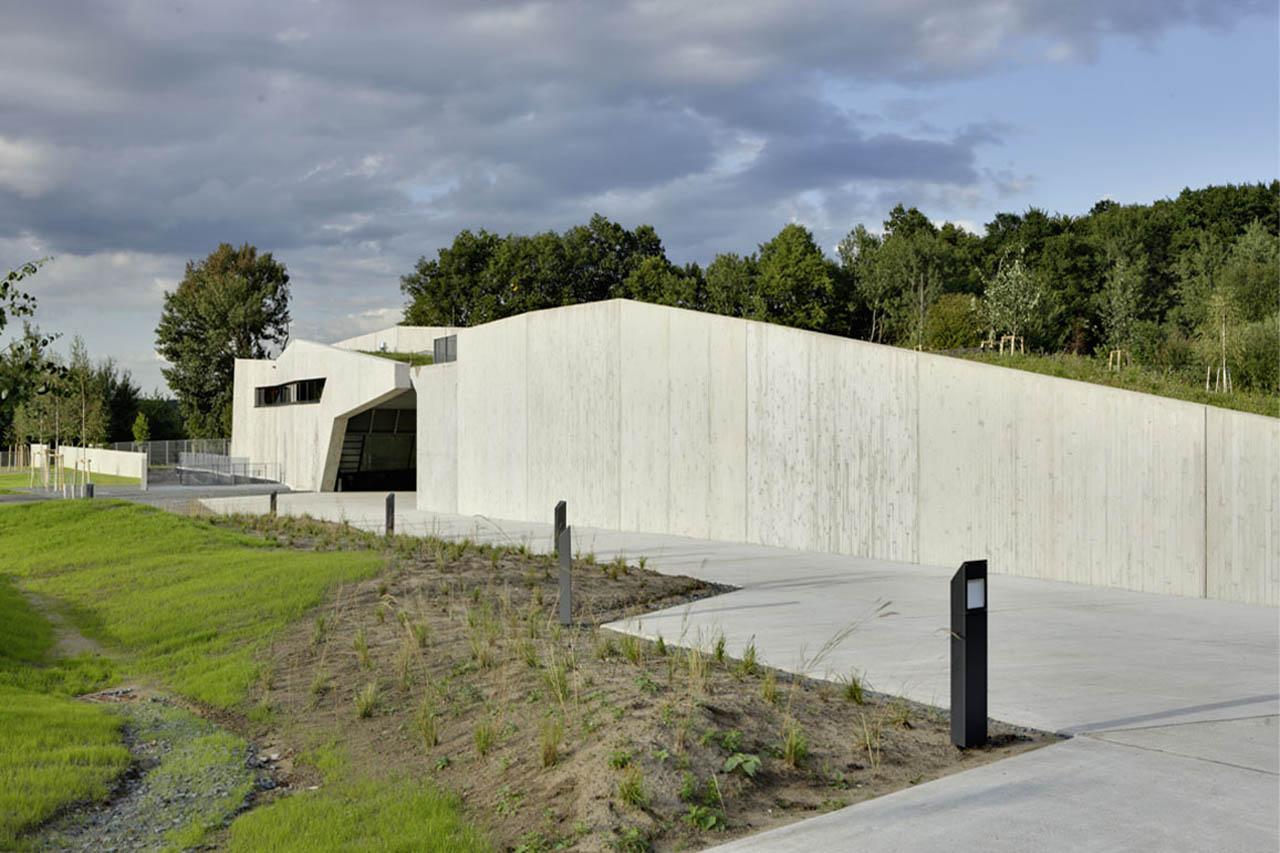 Modern concrete visitor centre building with sloped roof and grassy approach path at the Messel Pit, Darmstadt.