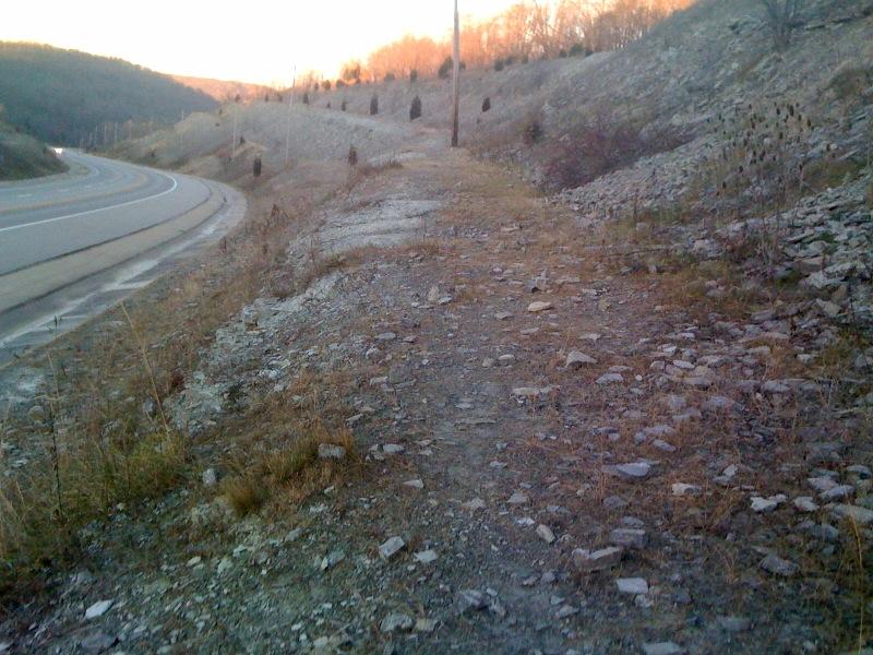 Roadside cutting with a slope of crumbled limestone fragments along a curving highway at dusk near St. Leon, Indiana.