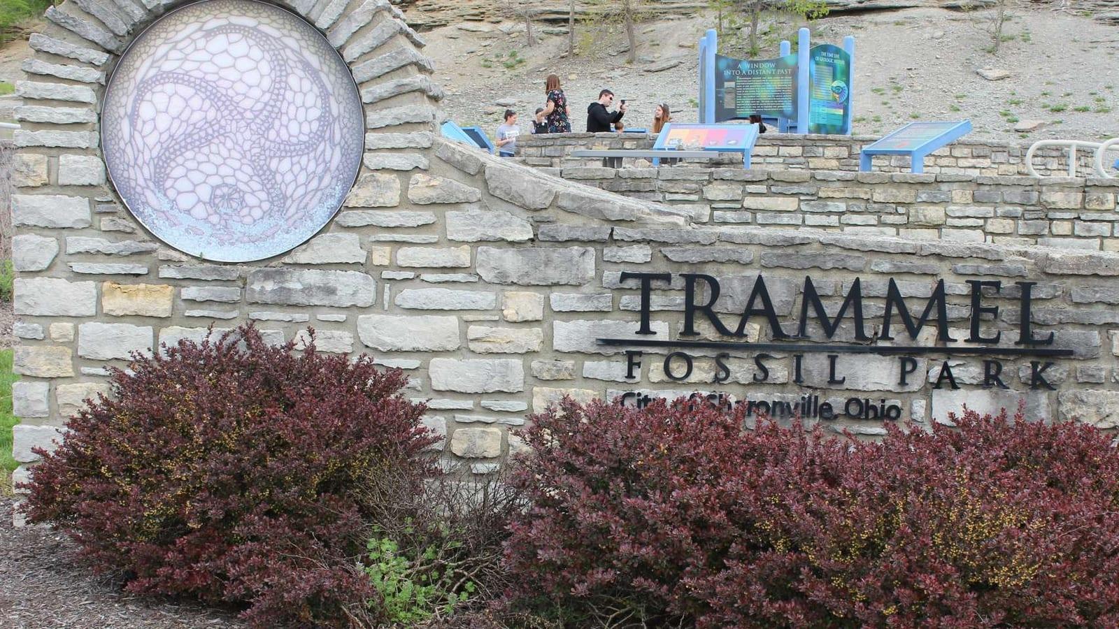 Stone monument with circular fossil mosaic and people on the platform above at Trammel Fossil Park, Sharonville, OH.